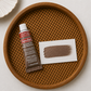 Rubin Buff wax metallic finish tube and swatch on a woven wooden tray